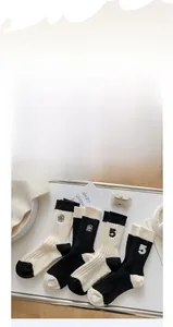 Detail of wool socks featuring floral embroidery and ribbed texture in black and white