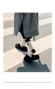 Close-up of off-white ribbed wool socks with black number 5 embroidery and slippers