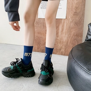 Women's 1977 blue crew socks styled with black chunky platform sneakers and green accents