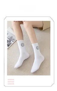Close-up of white cotton ribbed crew socks with a black smiley face embroidery detail