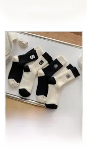 Detail view of black and white knit crew socks with rose embroidery and number 5 accent