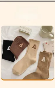 Détail de chaussettes en coton côtelé avec broderie A en diverses couleurs terreuses