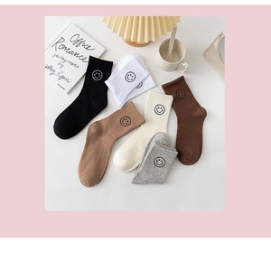 Flat lay of cotton rib-knit crew socks with cute embroidered smiley faces in earthy tones