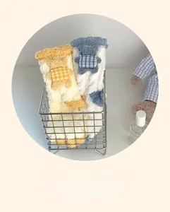 Détail de chaussettes d'hiver en polaire corail avec oursons 3D dans un panier en métal
