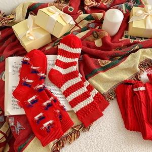 Cozy festive red cotton socks set with wave patterns and tassels on knit background