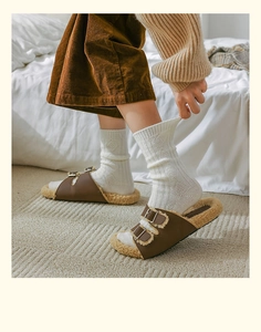 Close-up of brown faux leather winter slippers with plush beige wool lining and metal buckles