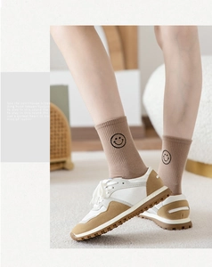Detail of cotton crew socks featuring a black smile face pattern with casual lace-up sneakers