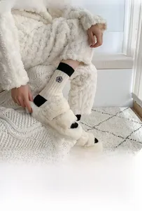 Detail of wool socks with camellia embroidery and plush slippers in a cozy home setting