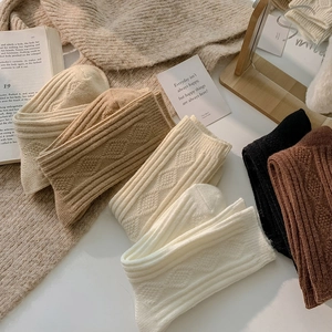 Thick diamond knit wool blend socks in warm neutral colors displayed on a cozy background