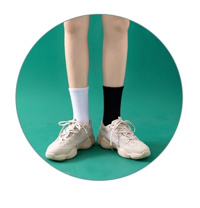 Nahaufnahme von beigen Chunky-Sneakern mit Mesh-Einsätzen und Socken auf grünem Hintergrund