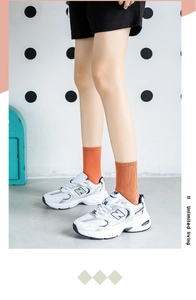 Detail showing orange ribbed cotton socks with retro white and blue chunky sneakers