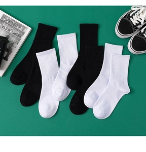 Nahaufnahme von schwarzen und weißen gerippten Baumwollsocken auf dunkelgrünem Grund