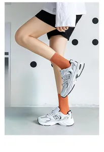Close-up of retro chunky sneakers paired with orange mid-calf cotton socks and blue accents