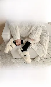 Detail of wool socks featuring elegant rose embroidery and soft white plush slippers