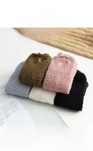 Détail de chaussettes en polaire corail avec texture pelucheuse et broderie patte de chat