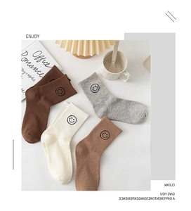Detail of four pairs of ribbed cotton socks with embroidered smiley faces in neutral tones
