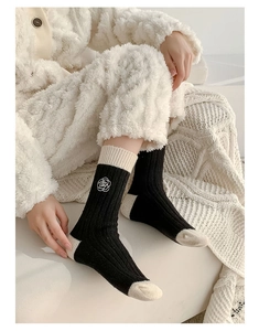 Detail of black wool sock with white camellia embroidery and ribbed knit texture
