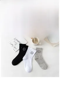 Detail of cotton crew socks featuring cute smiley face embroidery in black and white