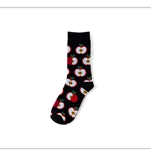 Detail of cotton crew sock featuring vibrant red apple patterns on a black background