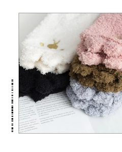Gros plan de chaussettes en polaire corail avec broderie dorée et texture douce de fibres
