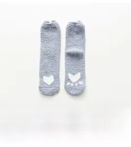 Détail de chaussettes en velours corail bleu avec motifs cœurs blancs et texture douce