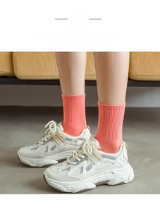 Detail of coral pink ribbed mid-calf socks paired with white chunky sports sneakers