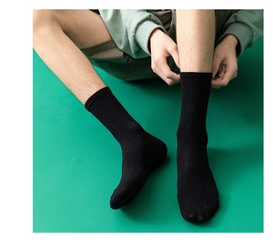 Detail von schwarzen Baumwoll-Rippsocken mit elastischer Textur auf grünem Hintergrund