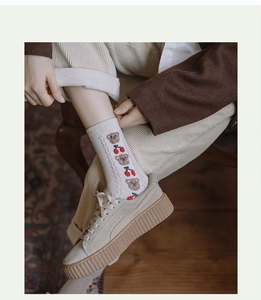 Close-up of thick wool socks with bear pattern and cable knit texture in cream