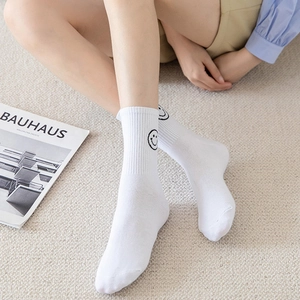 White crew socks with black smiley face pattern and ribbed cuffs for stylish daily wear
