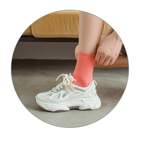 Detail of coral ribbed crew socks paired with off-white chunky mesh sneakers