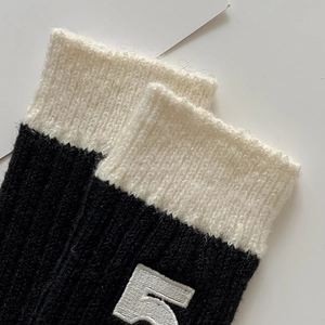 Thick black wool knit socks with cream ribbed cuff and white number 5 embroidery detail
