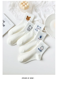 Detail of white cotton crew socks featuring cute cartoon bear embroidery and ribbed cuffs