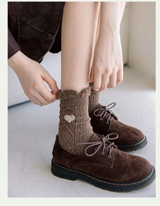 Close-up of thick brown wool socks with white heart embroidery paired with leather shoes