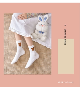 Detail of white cotton socks featuring brown bear embroidery and HI BEAR text design