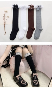 Dettaglio di calze alte stile Lolita con pizzo delicato e fiocchi decorativi in seta