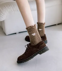 Detail of dark brown cable knit wool socks with heart embroidery and wavy cuffs