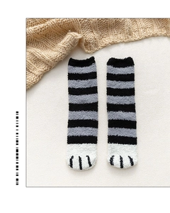 Detail of coral fleece cat claw socks with black and gray stripes on textured carpet