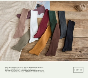 Détail de chaussettes hautes en coton côtelé en neuf couleurs vintage sur un tapis tricoté