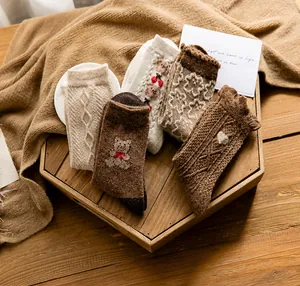 Macro detail of thick wool socks with bear embroidery and cable knit texture in earthy tones