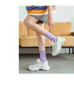 Close-up of purple ribbed mid-calf socks paired with stylish white chunky sneakers