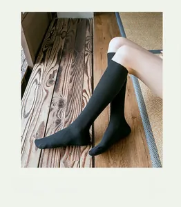 Texture détaillée des chaussettes hautes en coton noir côtelé sur sol bois