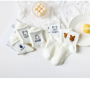 Detail of five white cotton crew socks with cute embroidered bear and rabbit patterns