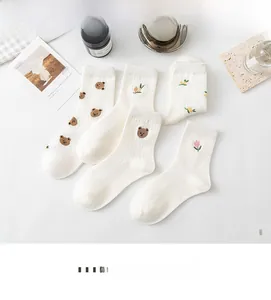 Detail of five pairs of white ribbed crew socks with cute bear and floral embroidery
