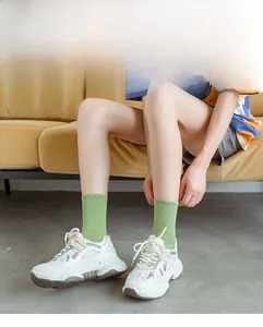 Close-up of light green ribbed cotton socks paired with stylish white platform sneakers