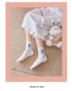 Detail of white cotton sock featuring blue bunny embroidery and Lucky text on ankle