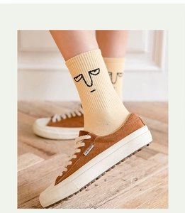 Close-up of cream cotton socks with cartoon face paired with brown suede sneakers