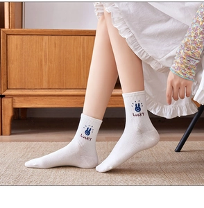 Detail of white cotton mid-tube socks featuring a blue rabbit and Lucky embroidery
