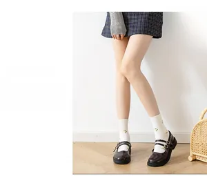 Detail of white cotton socks with yellow floral pattern and brown Mary Jane shoes