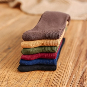 Set of six colorful ribbed cotton mid-calf socks stacked on a natural wooden surface