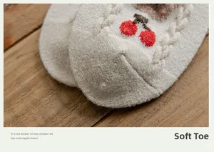 Detail of wool knit sock toe with cable pattern and cherry embroidery on wood background